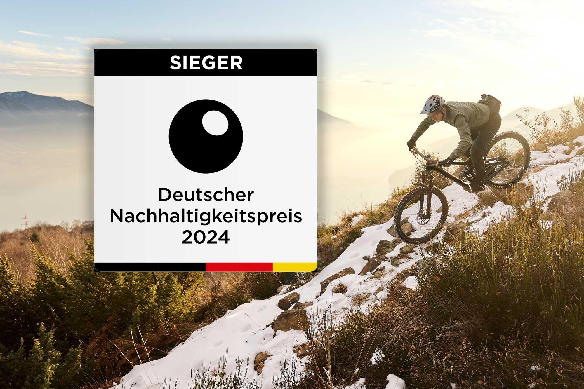 Logo Deutscher Nachhaltigkeitspreis im Hintergrund ein Mountainbikefahrer auf schneebedeckter Strecke in den Bergen.
