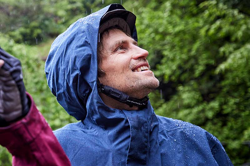 Mann mit Regenjacke schaut in den Himmel