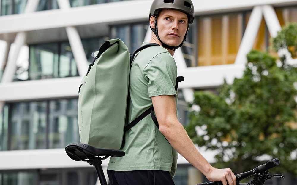 Man staat in de stad met fiets en rugzak