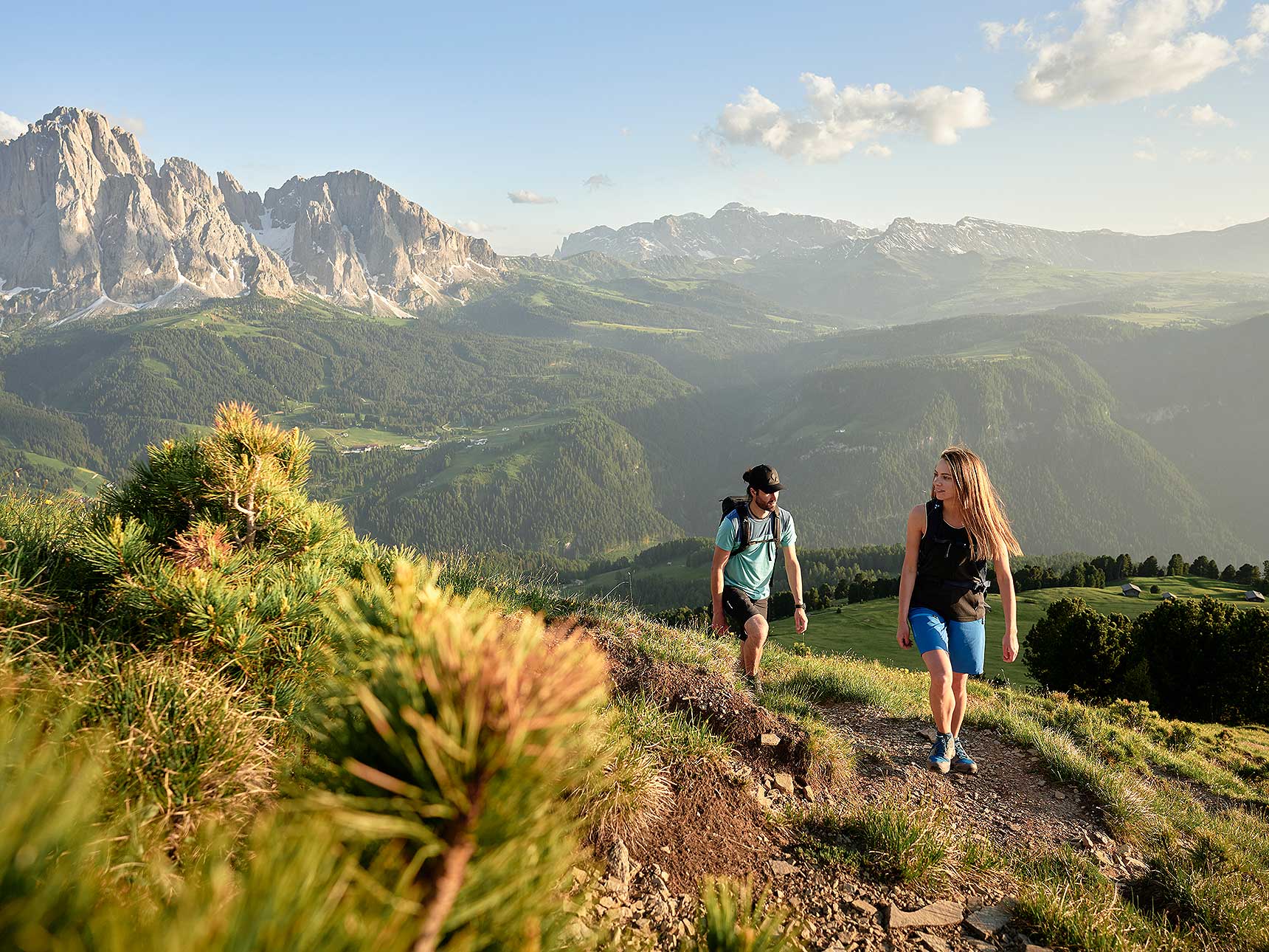 two people hiking through nice landscape with mountains in the background