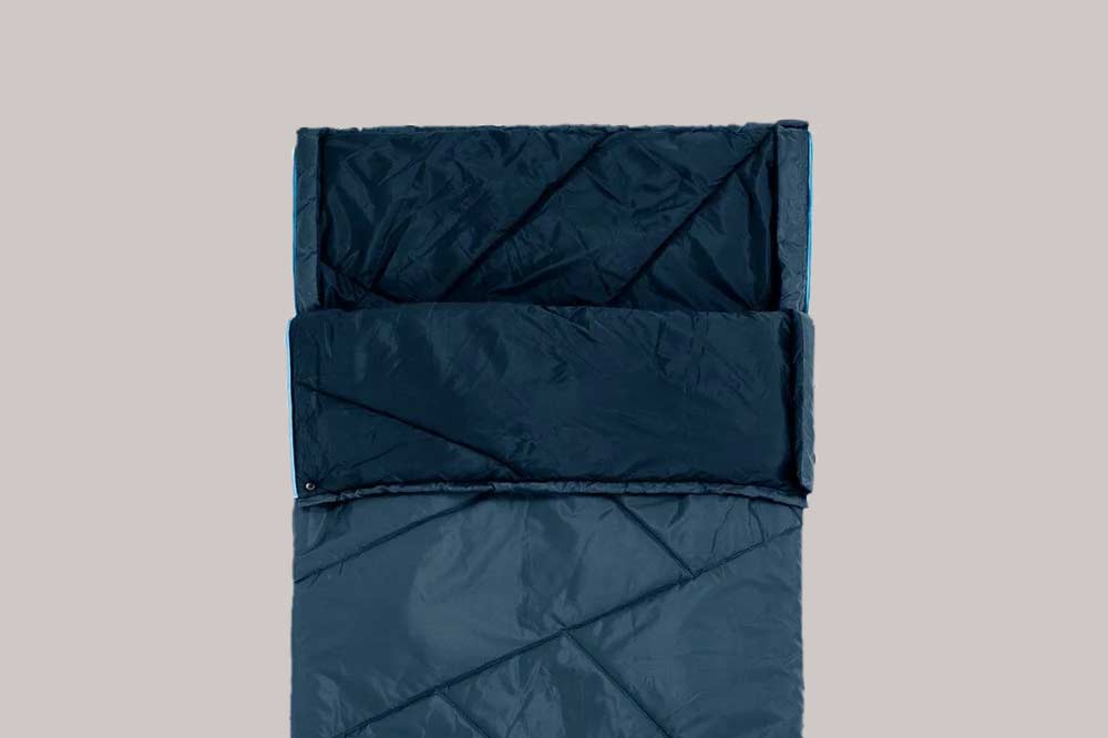 blauer Schlafsack liegt auf beigem iIntergrund