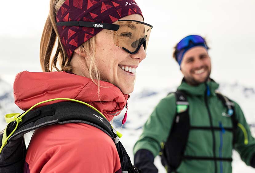 Zwei Personen lächeln fröhlich in Skiausrüstung in den Bergen