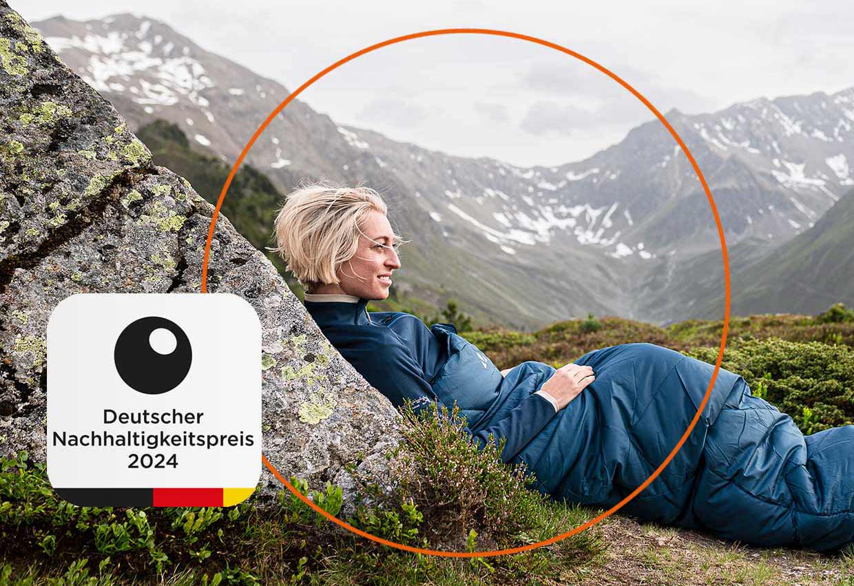 Frau in Schlafsack auf Bergwiese, im Vordergrund das Deutscher Nachhaltigkeitspreis Logo