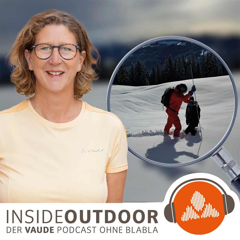 die Podcast Moderatorin steht vor einem Skitour-Lawinensuchendem