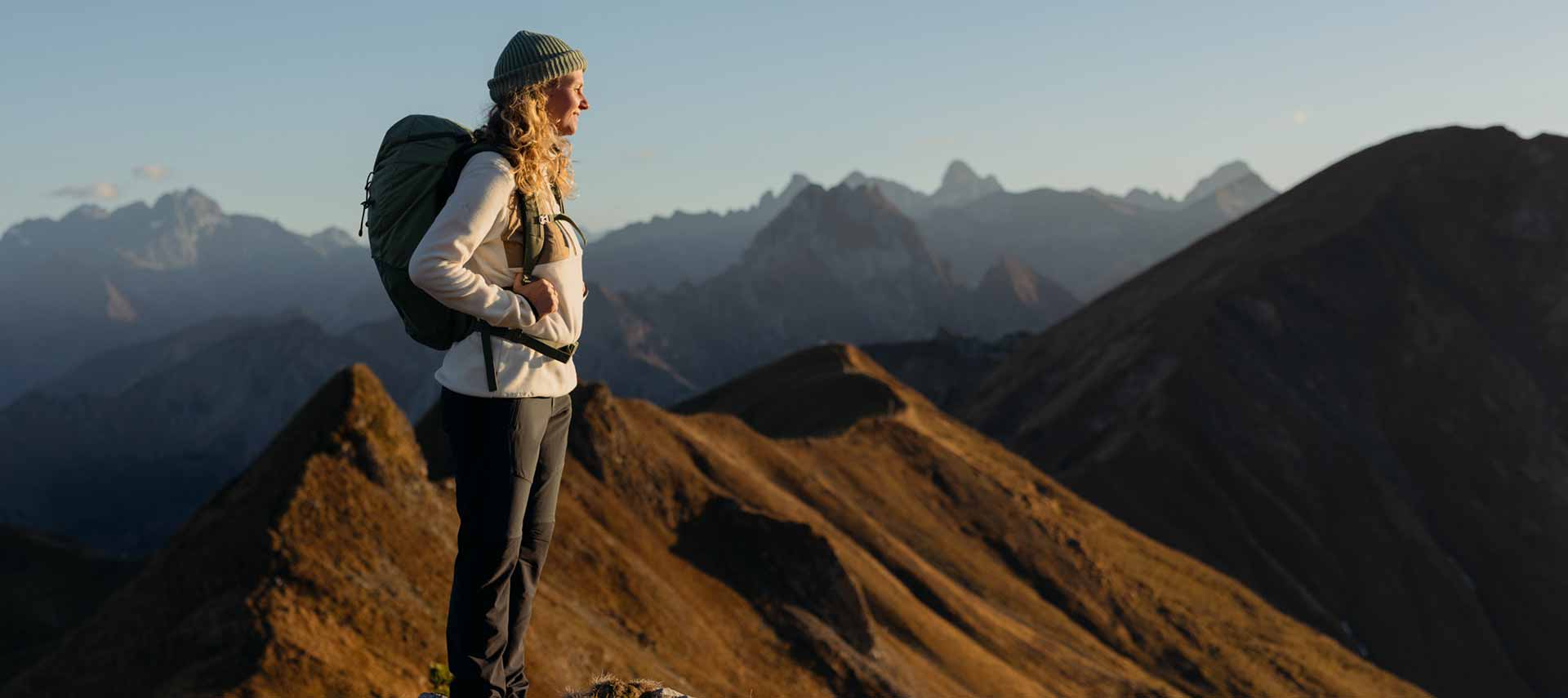 Frau steht auf Berggipfel und blickt in die Ferne