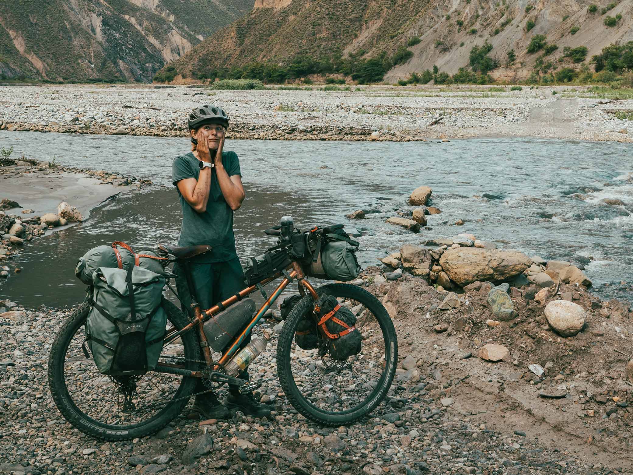 Young woman standing with bicycle in front of river