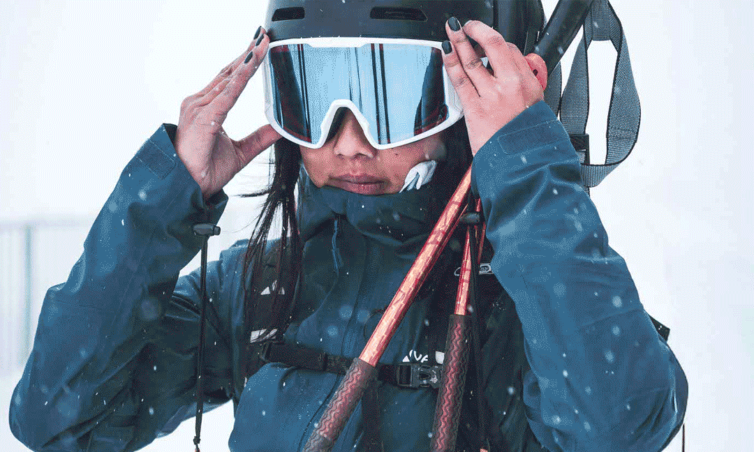 Frau im Schnee mit Helm und zwei M&auml;nner in Jacken