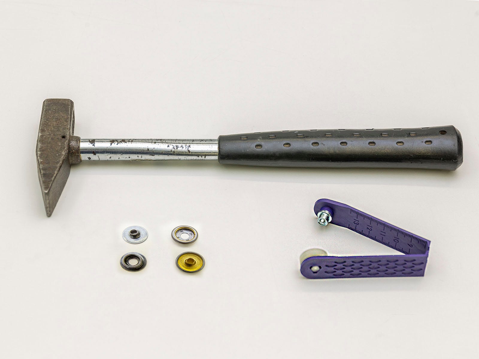 Ein Hammer, ein Ersatz-Druckknopf und ein Lochwerkzeug