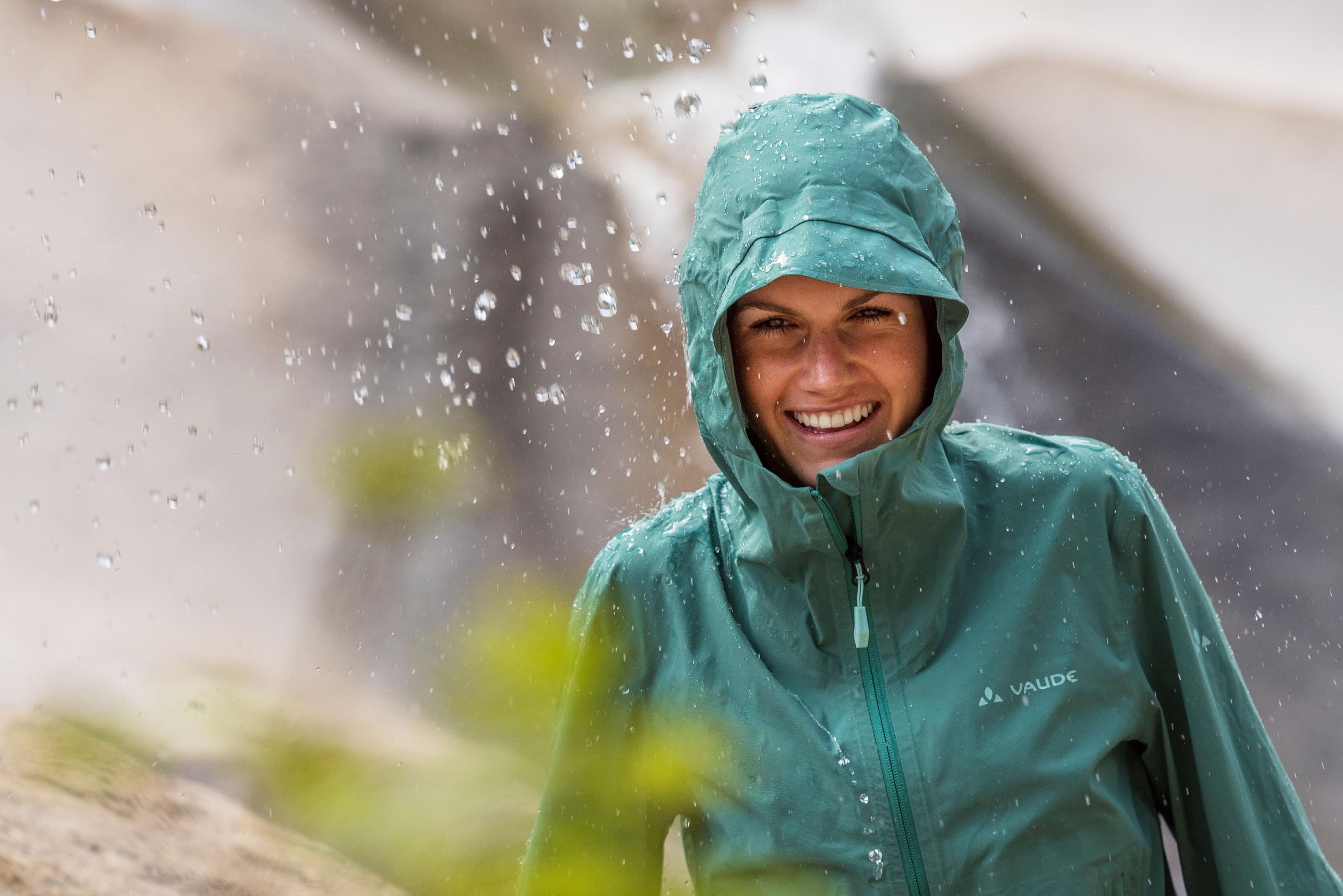 Frau mit Kapuze auf dem Kopf im Regen, Wassertropfen perlen an der VAUDE Regenjacke ab