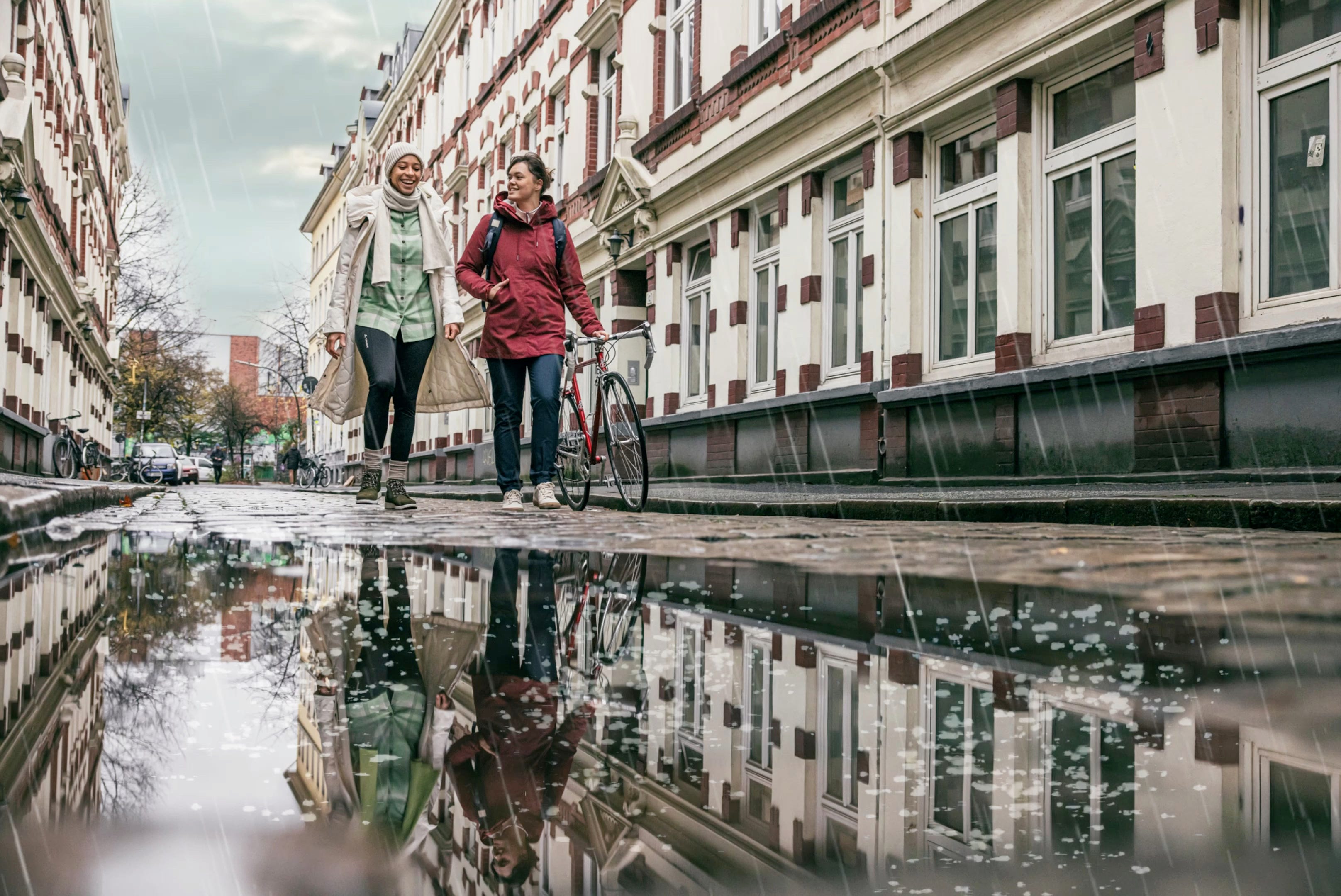 Zwei Frauen laufen bei Regen durch die Straße