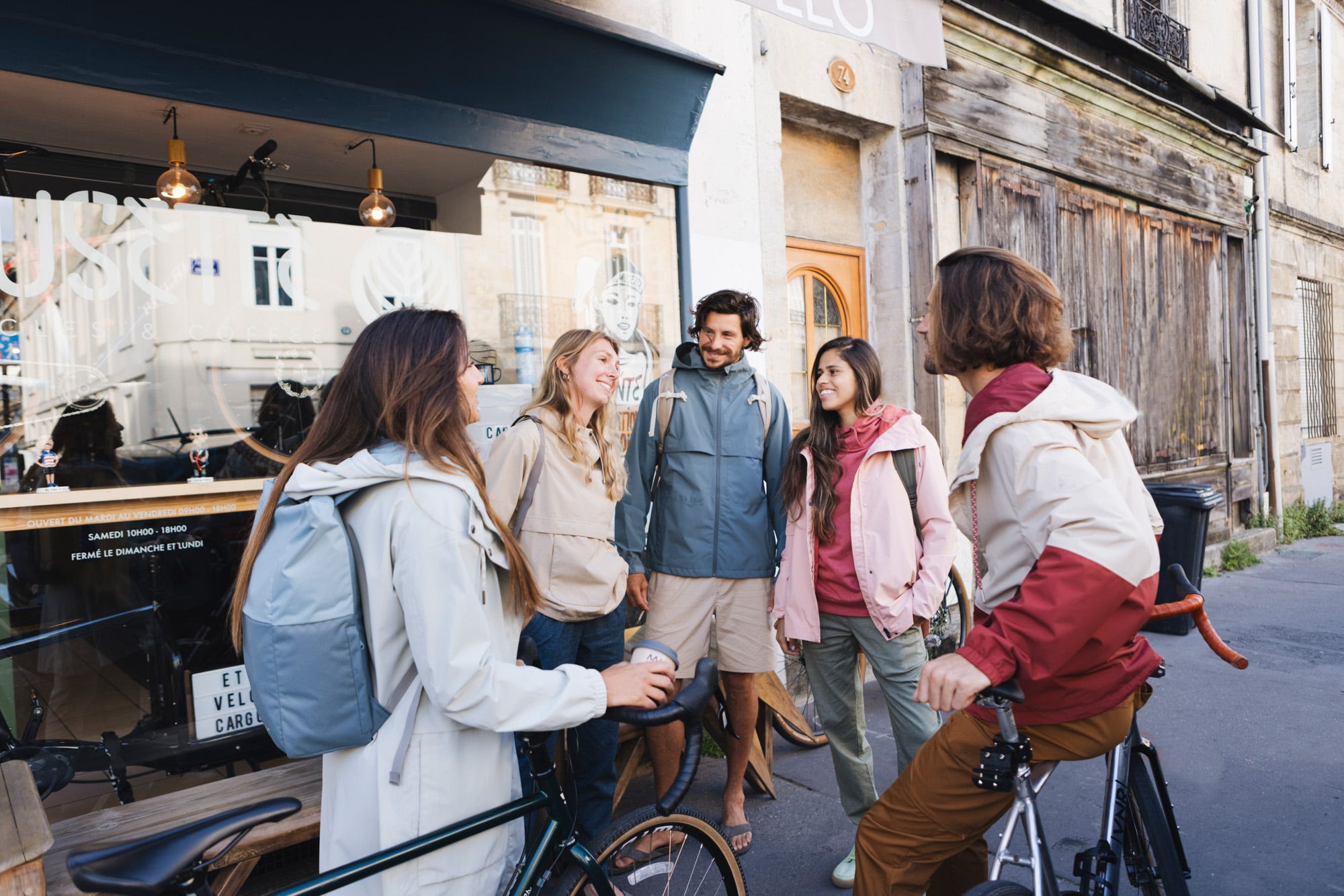 Eine fröhliche Gruppe junger Menschen in der Stadt mit Outdoorjacken.