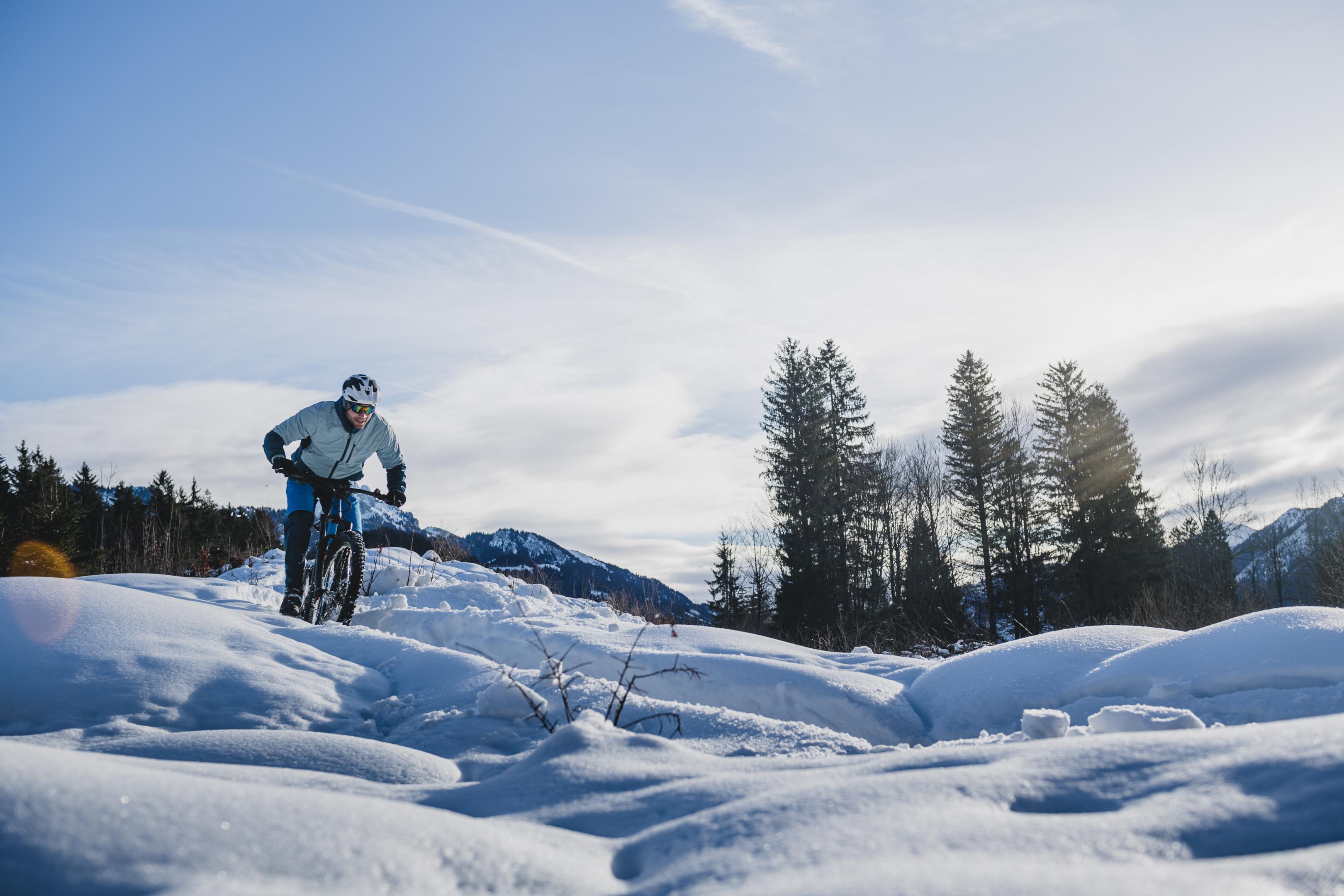 Ein Mountainbiker fährt durch eine verschneite Schneelandschaft