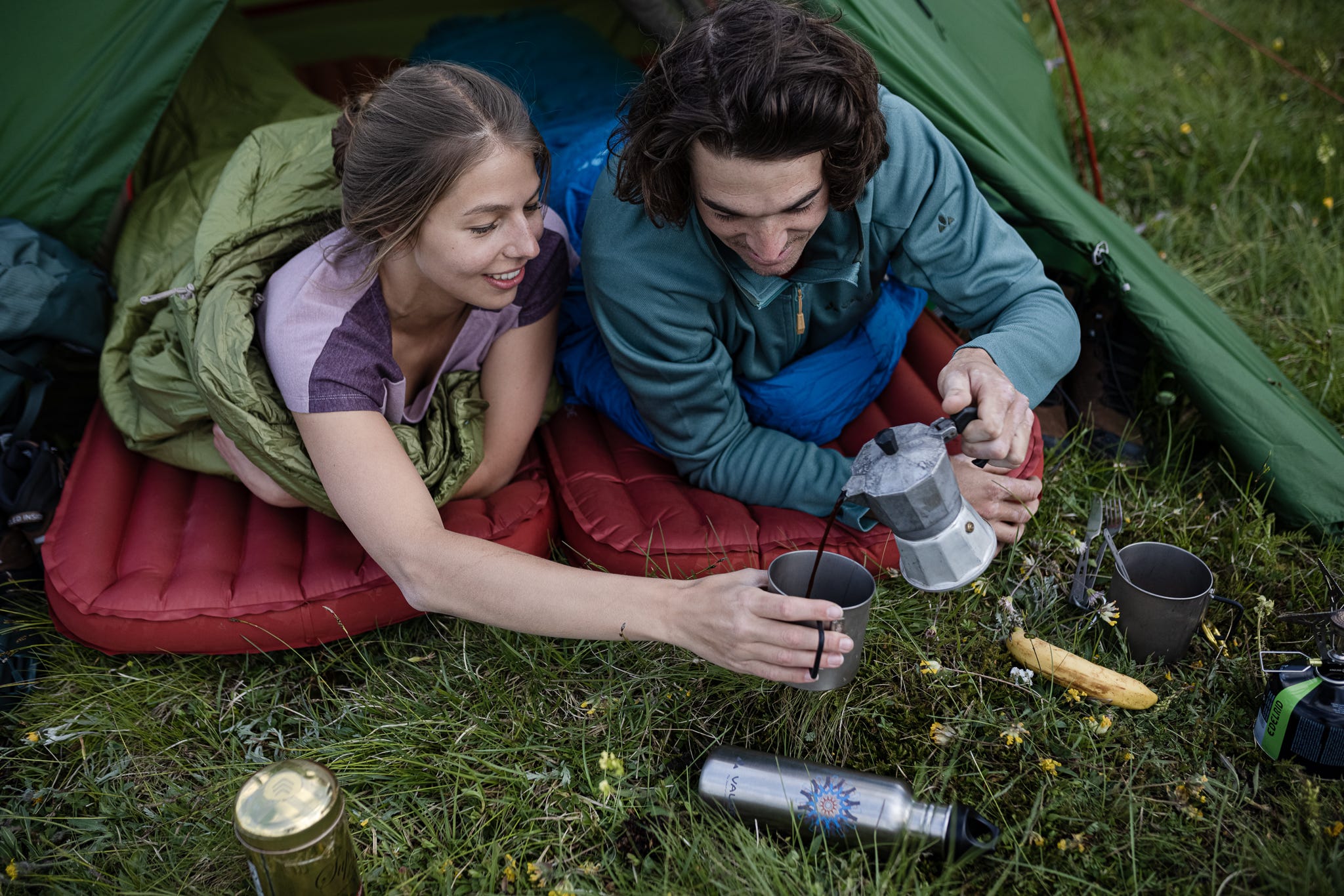 Frühstück mit Kaffee vom Gaskocher beim Zelten auf grüner Wiese