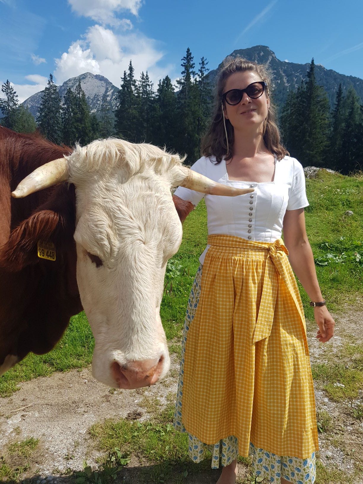 Frau mit Tracht steht neben einer Kuh.