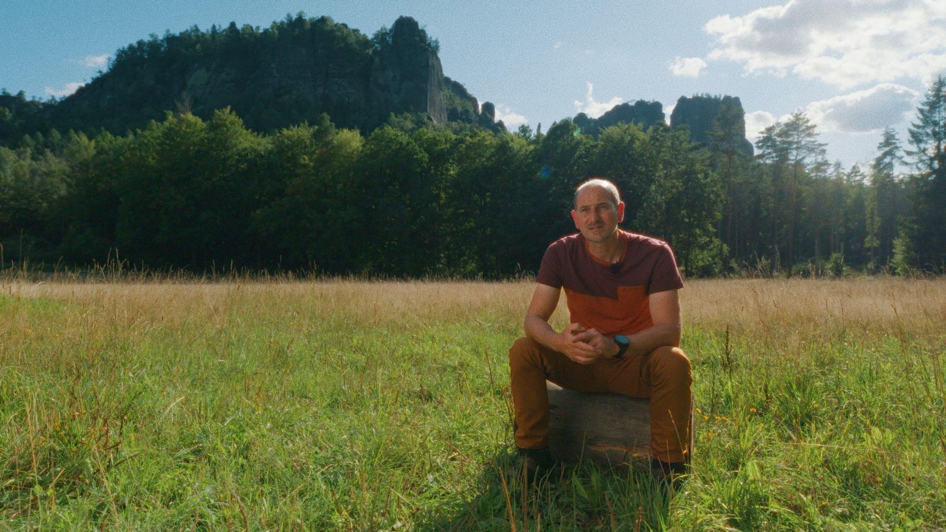 Mann sitzt auf Wiese in Natur