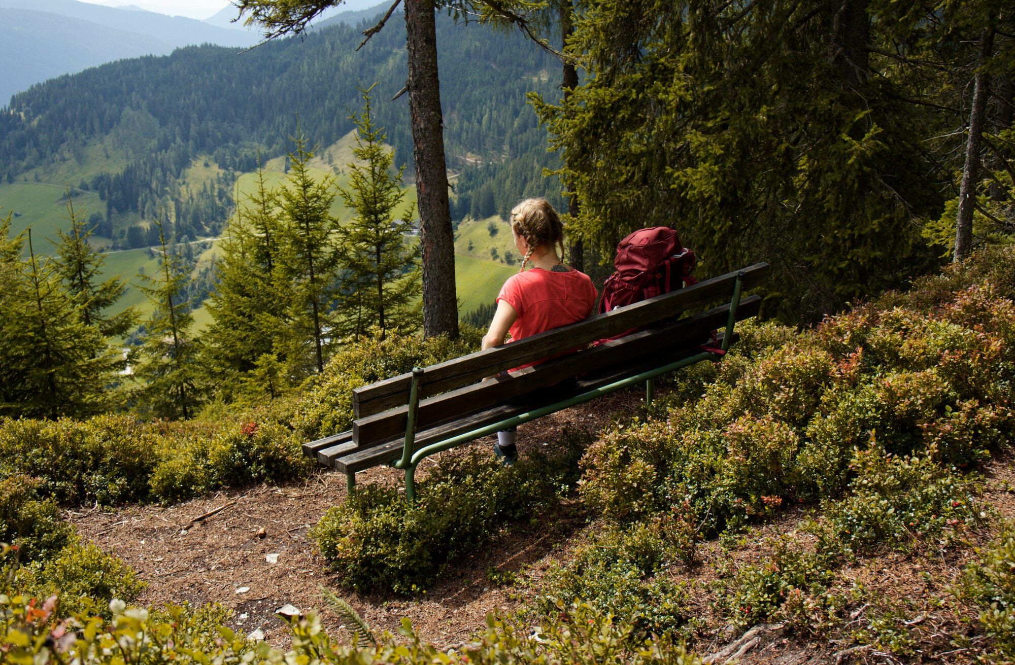 Frau genießt den Ausblick auf einer Rastbank