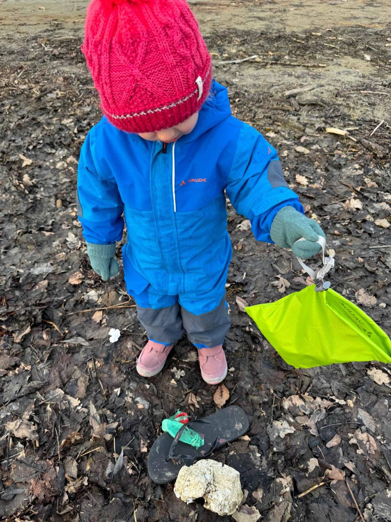 Ein Kind mit VAUDE Plogging Bag hat einen Flip Flop entdeckt.