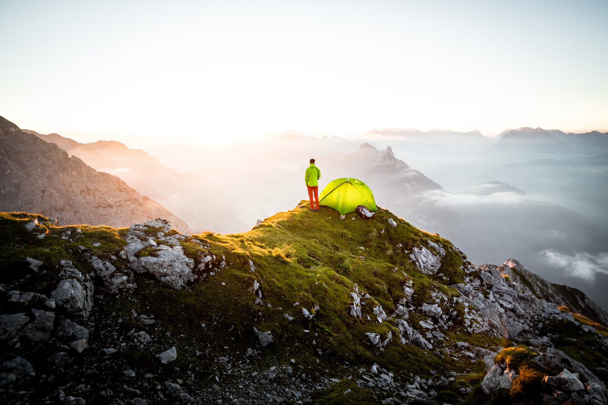 Homme debout sur une montagne à côté d'une tente