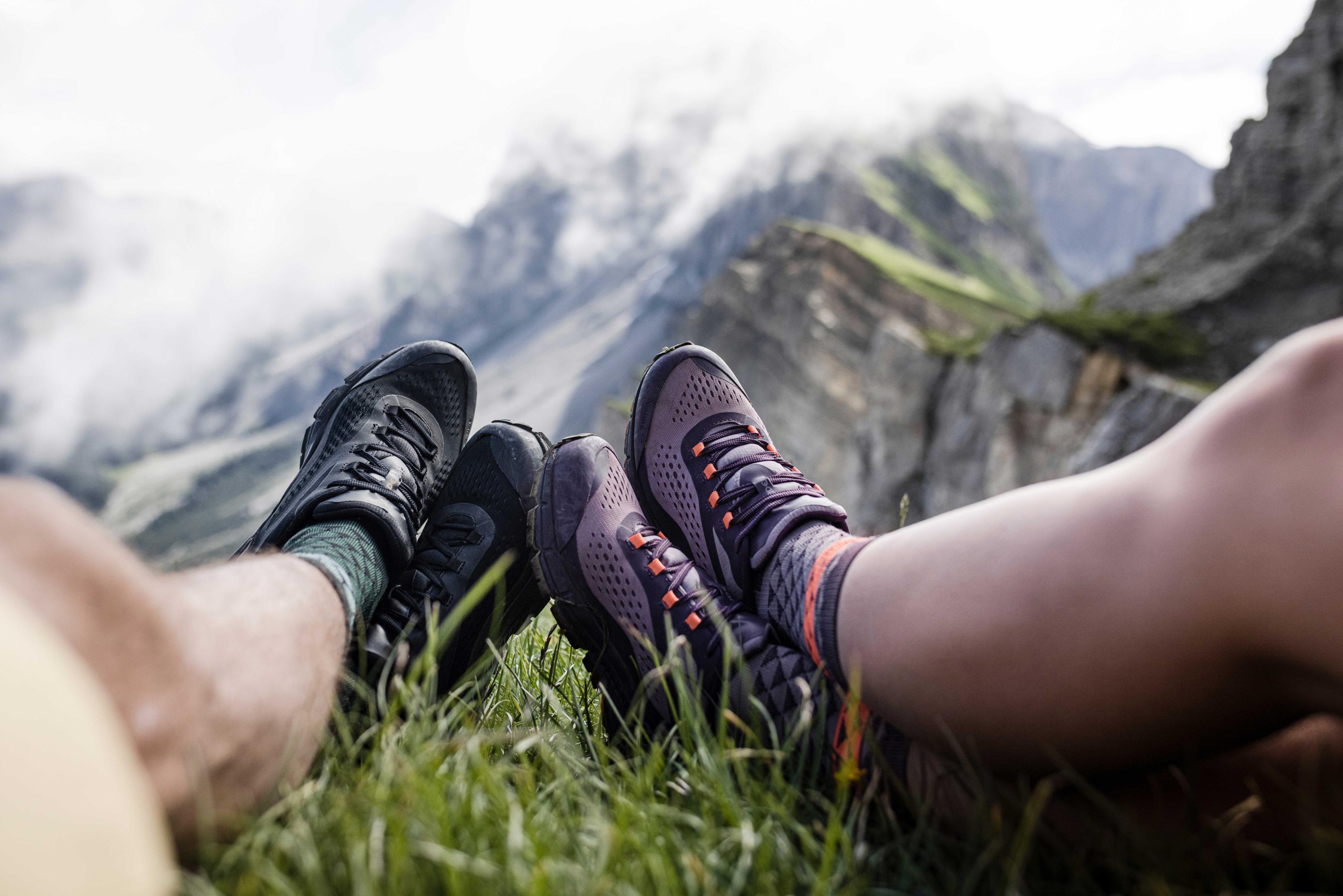 2 Paar Füße von Wandernden mit Blick auf die Berge