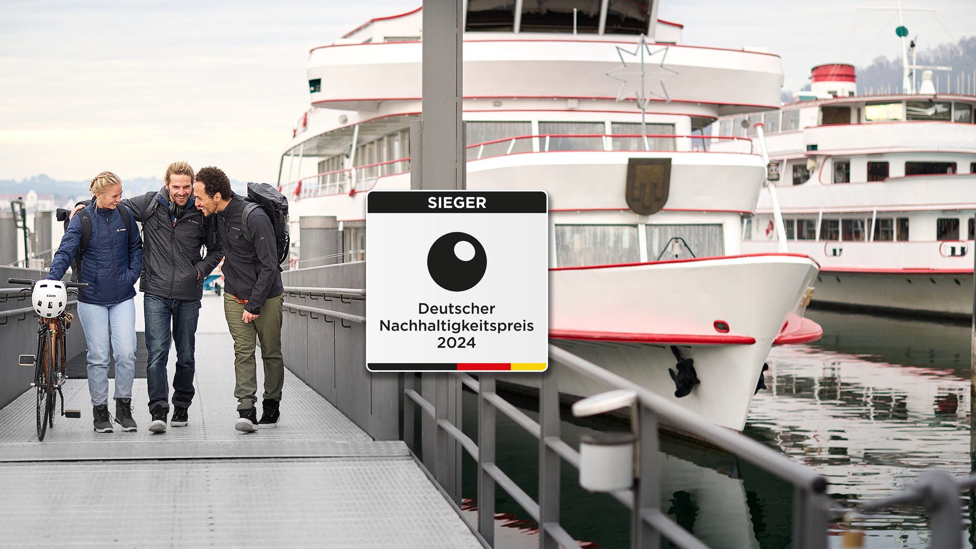Drei Personen am Hafen, in der Mitte das Logo des deutschen Nachhaltigkeitspreis Drei Personen am Hafen, in der Mitte das Logo des deutschen Nachhaltigkeitspreis
